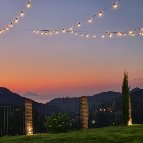 a string of lights over a fence at sunset at Arcaloro Resort Rooms in SantʼAngelo di Brolo