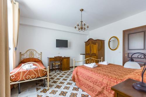 a hotel room with two beds and a television at Arcaloro Resort Rooms in SantʼAngelo di Brolo