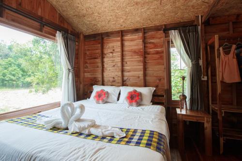 a bedroom with a bed with red flowers on it at บ้านสวนแก้วคำแพง Baan Suan Kaew Khampaeng in Udon Thani