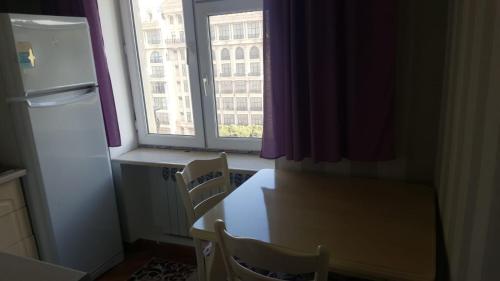 una cucina con un tavolo, un frigorifero e una finestra di Квартира a Baku
