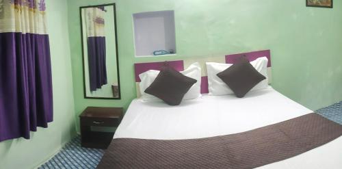 a bedroom with a white bed with black pillows at Radha Krishna Home in Varanasi
