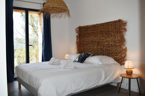 ein Schlafzimmer mit einem weißen Bett mit einem großen Fenster in der Unterkunft Amandula Bergerie Sotta hyper cozy in Sotta