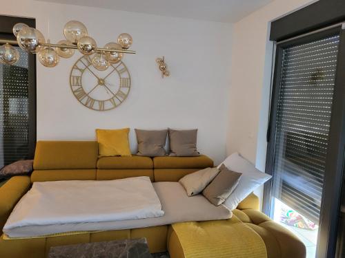 a living room with a couch and a clock on the wall at Apartman Dalmatino in Petrcane