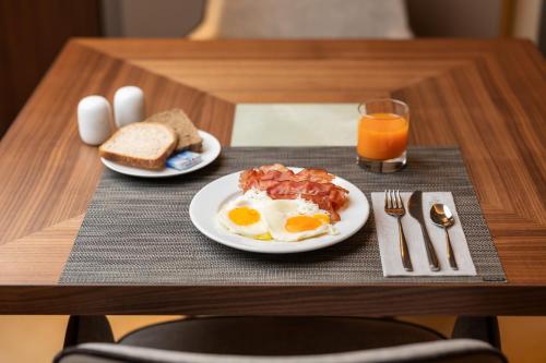 a breakfast plate of eggs bacon and toast and a glass of orange juice at Villa Rosa Hotel Desenzano in Desenzano del Garda