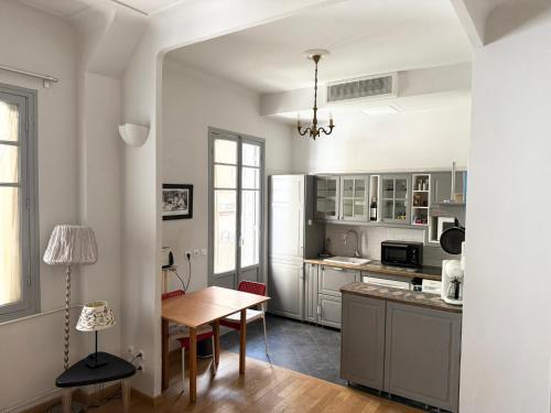une cuisine avec des armoires blanches et une table à l'intérieur dans l'établissement Charmant studio avec terrasse, à Nice