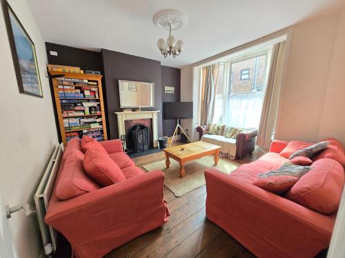 a living room with two red couches and a fireplace at Lavender House Weymouth in Weymouth