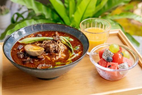 a bowl of soup on a tray with a bowl of fruit at The Yard Boutique Hotel Shanghai 一隅酒店上海虹桥漕河泾店 in Shanghai