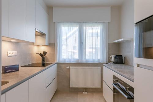 eine Küche mit weißen Schränken und einem Fenster in der Unterkunft Huswell - Villa Near Beach with Double Parking in Oostduinkerke