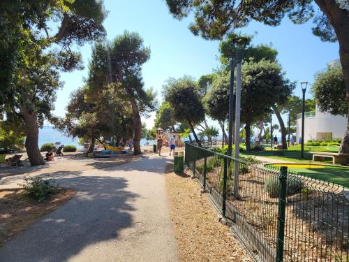 a park with a fence and trees and a sidewalk at Apartman Dalmatino in Petrcane