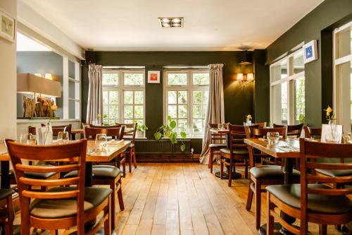 a restaurant with wooden tables and chairs and windows at The Bell Inn, Ladbroke in Ladbroke