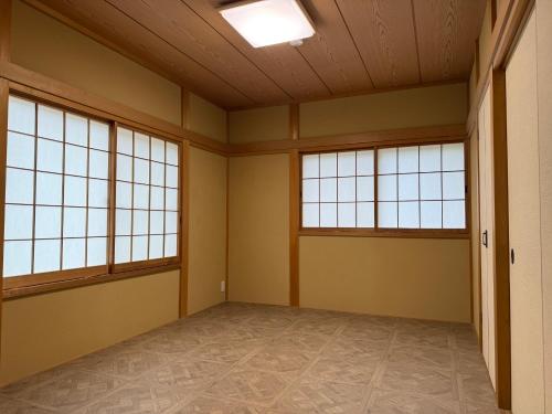 an empty room with three windows and a ceiling at コテージ33 in Nasu