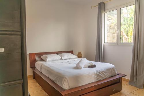 a bedroom with a bed with white sheets and a window at Villa Ile d'Eden - Vue mer-Piscine - By Sister Home in Sainte-Marie