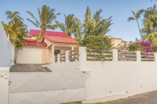 a house with a white fence and palm trees at Villa Ile d'Eden - Vue mer-Piscine - By Sister Home in Sainte-Marie
