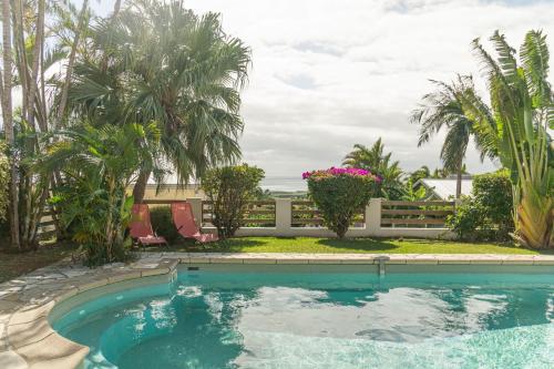 a swimming pool with palm trees and a fence at Villa Ile d'Eden - Vue mer-Piscine - By Sister Home in Sainte-Marie
