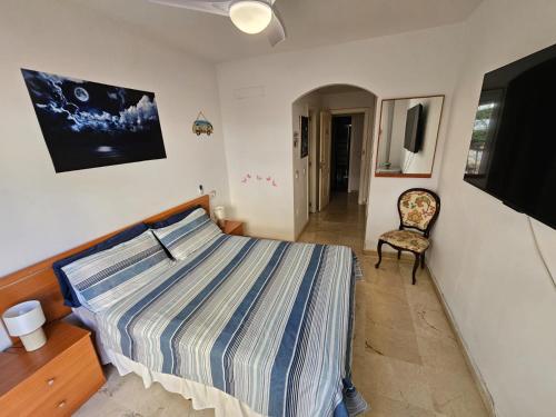 a bedroom with a bed and a chair and a tv at Bienvenido a tu habitacion in Málaga