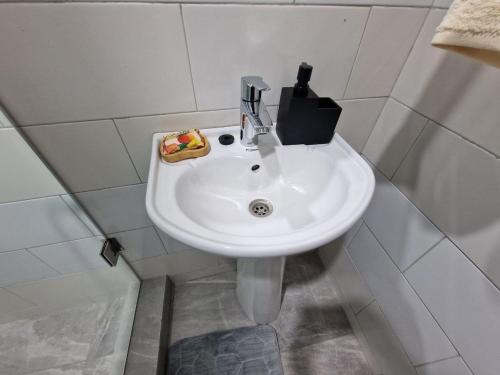 a white sink in a white tiled bathroom at Kirpal Villa in Kwabenya