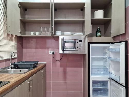 a kitchen with pink tile walls and a refrigerator at Kirpal Villa in Kwabenya