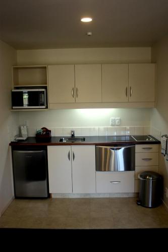 a kitchen with white cabinets and a stainless steel sink at Cedar Grove Motor Lodge in Nelson