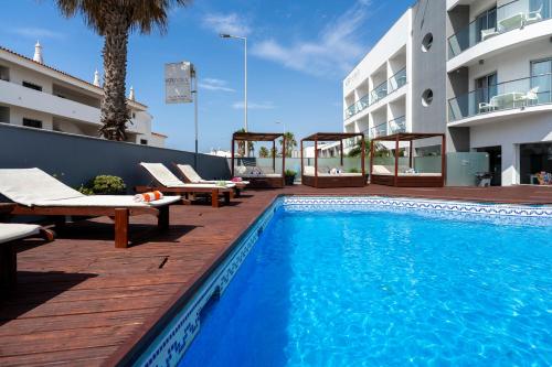 a swimming pool with lounge chairs and a building at KR Hotels - Albufeira Lounge in Albufeira