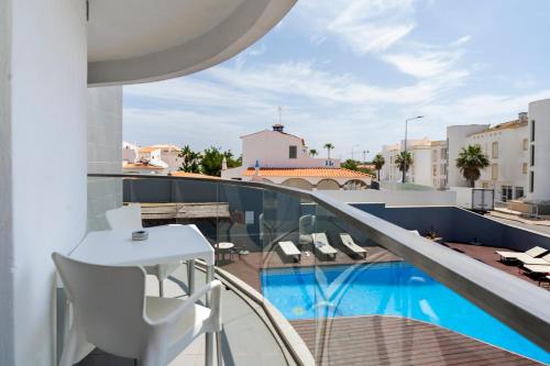 a balcony with a table and chairs and a swimming pool at KR Hotels - Albufeira Lounge in Albufeira