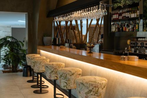 a row of stools in a bar with a counter at Eliros Mare Beachfront Poem Hotel in Georgioupolis