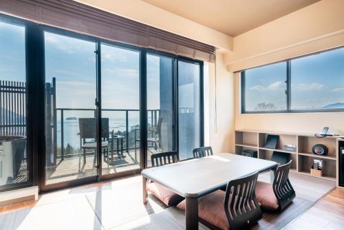 a living room with a table and chairs and large windows at LiVEMAX RESORT Miyahama Ocean View in Hatsukaichi
