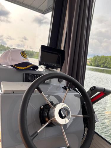 a boat dashboard with a steering wheel and a monitor at Houseboat -La Calma- Czaplinek in Czaplinek