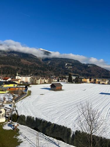 un grand champ enneigé avec une ville et des montagnes dans l'établissement Apartement Lampi, à Kötschach-Mauthen