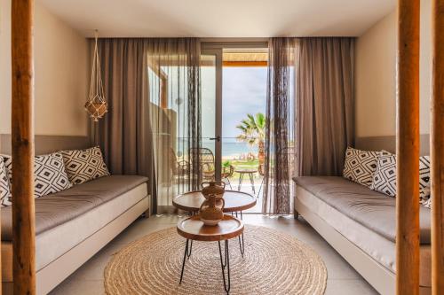 a living room with a couch and a table at Eliros Mare Beachfront Poem Hotel in Georgioupolis