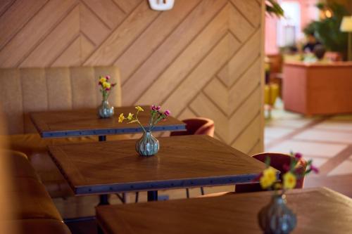two wooden tables with vases with flowers on them at The July - Boat & Co in Amsterdam