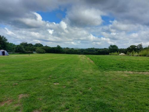 a field with a dirt road in the middle of it at Hopgarden Glamping and camping - Luxury furnished Bell tents & Shepherd huts plus camp field to pitch your own tents in Wadhurst