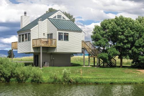 a house with a deck next to a body of water at Wyndham Pagosa Springs 2BR Apartment with Resort Access in Pagosa Springs
