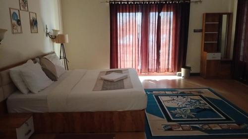 a bedroom with a large bed and a window at Clouds Inn Holidays Homes Stay in Ooty