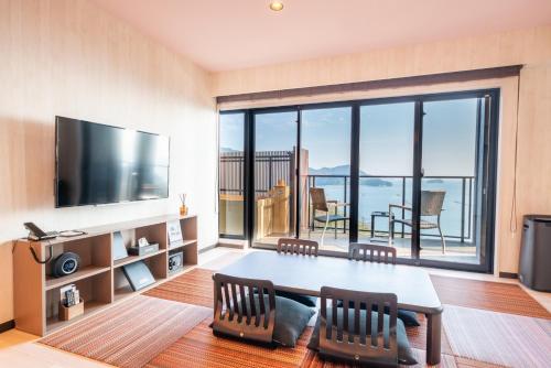 a living room with a table and a large window at LiVEMAX RESORT Miyahama Ocean View in Hatsukaichi