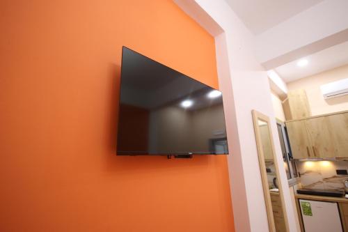 a flat screen tv hanging on a orange wall at Stef & Stam Nerantzis in Himare