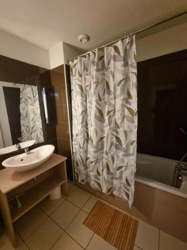 a bathroom with a sink and a shower curtain at Duplex avec piscine et sauna in Jausiers