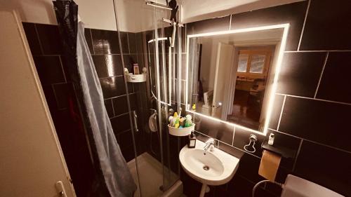 een zwart betegelde badkamer met een wastafel en een spiegel bij Sibejdo 3&4 in Varaždin