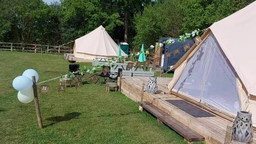 a group of tents in a field with balloons at Hopgarden Glamping and camping - Luxury furnished Bell tents & Shepherd huts plus camp field to pitch your own tents in Wadhurst