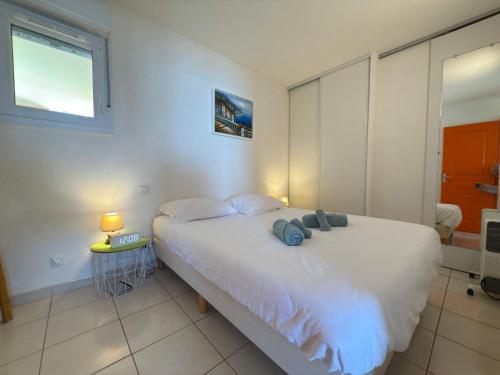 une chambre avec un grand lit blanc et une fenêtre dans l'établissement Valras- Loc Alizea Beach, à Valras-Plage