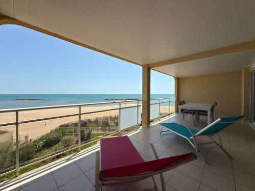 - un balcon avec une table et des chaises et la plage dans l'établissement Valras- Loc Alizea Beach, à Valras-Plage