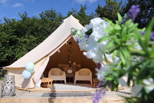 a white tent with chairs and a table at Hopgarden Glamping and camping - Luxury furnished Bell tents & Shepherd huts plus camp field to pitch your own tents in Wadhurst