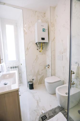 a white bathroom with a toilet and a sink at Casa Pan in Rome