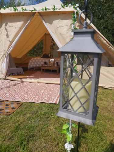 a lantern in front of a tent at Hopgarden Glamping and camping - Luxury furnished Bell tents & Shepherd huts plus camp field to pitch your own tents in Wadhurst