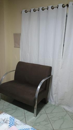 a chair sitting in front of a curtain at Espaço da Sisi in Hortolândia