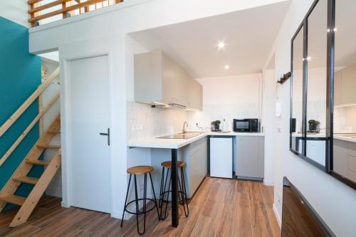 une cuisine avec des placards blancs et un escalier dans l'établissement Le Soyeux - 100m de la Gare & parking privé, à Roanne