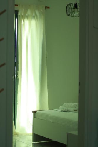 a white bedroom with a bed and a window at Euphoria Suite - Endless View in Ermoupoli