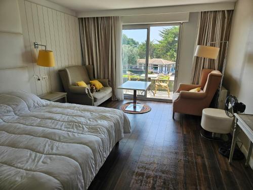 a hotel room with a bed and chairs and a window at Résidence Chiberta Anglet océan golf surf in Anglet
