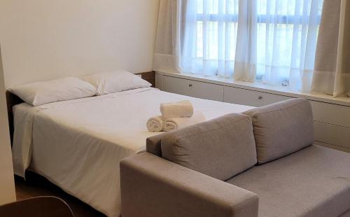 a bedroom with a bed and a couch and a window at Blend Coliving One - 2b in Ribeirão Preto