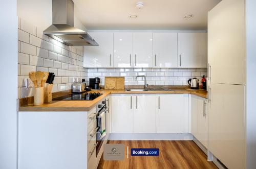 a kitchen with white cabinets and a wooden floor at Hotel-Quality Flat By Paul & Malin Properties Short Term Rental Salford With Great City Access in Manchester