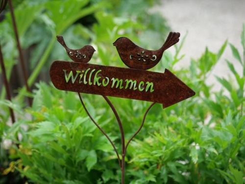 a sign in a garden with two birds on it at Appartements im Park in Krumpendorf am Wörthersee